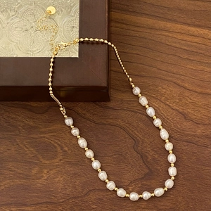Detailed close-up of natural freshwater pearl necklace with golden beads and lobster clasp