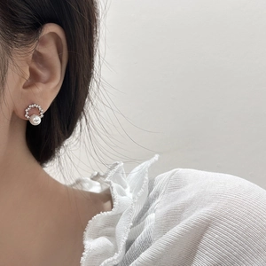 Elegant pearl and zircon stud earrings with silver ring detail shown on a model
