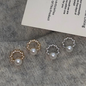 Elegant gold and silver wreath stud earrings with white pearls on a soft grey fabric