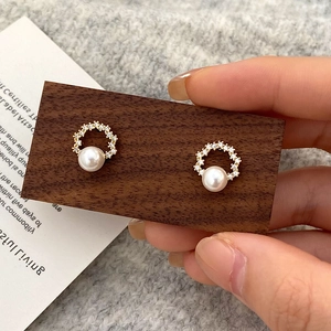 Detail of elegant gold-tone hoop earring with micro-pave crystals and a white pearl charm