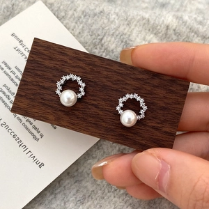 Detailed close-up of a silver pearl stud earring featuring a zircon-encrusted round hoop