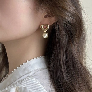 Boucles d'oreilles cœur et perle vintage dorées portées avec un col en dentelle
