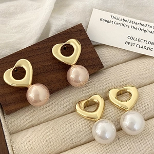 Boucles d'oreilles cœur vintage dorées avec perles blanches et roses sur présentoir