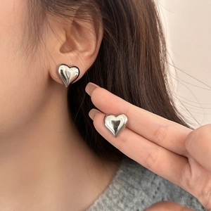 Chic silver heart stud earrings with a high-shine mirror finish worn by a model