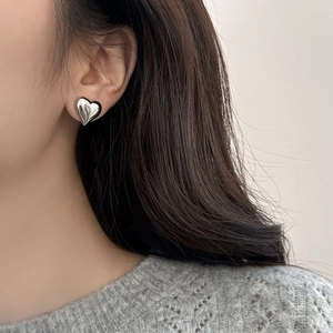 Detailed view of silver heart-shaped stud earring worn on model for a trendy look