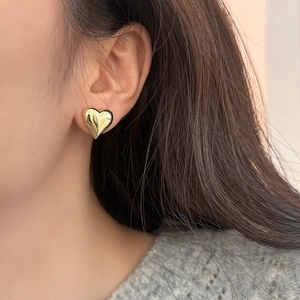 Elegant 3D golden heart stud earrings shown on model for a minimalist fashion look
