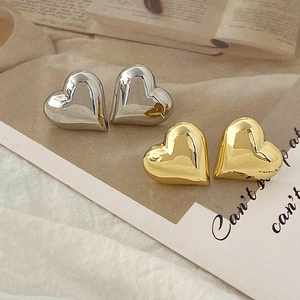 Detailed view of heart-shaped stud earrings in polished gold and silver finishes