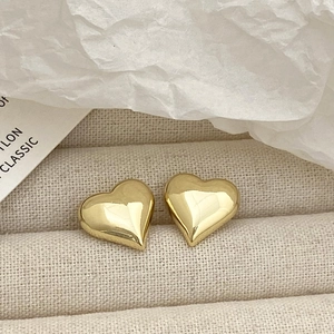 Macro view of gold heart stud earrings with a polished finish on a jewelry tray