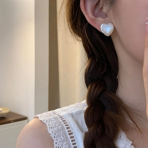 Close-up of elegant heart-shaped pearl stud earrings with silver edges on model