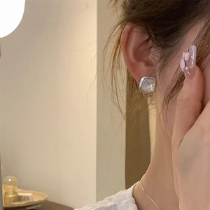 Close-up of a model wearing square silver earrings with white mother of pearl inlay