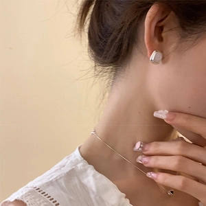 Detail of silver geometric square earrings and dainty chain necklace on a model