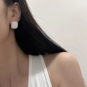 Close-up of minimalist square stud earrings with mother of pearl inlay on model ear