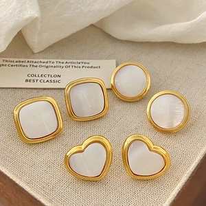 Detail of French geometric gold earrings set with white shell inlay in three shapes