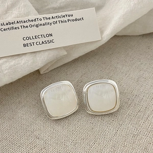 Macro view of geometric square earrings with silver finish and white mother of pearl inlay