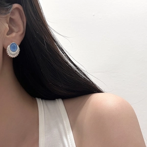 Gros plan d'une boucle d'oreille vintage en argent avec opale bleue sur mannequin