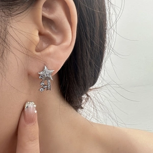 Close-up of sparkling star-shaped tassel earrings with pavé zircons on a model