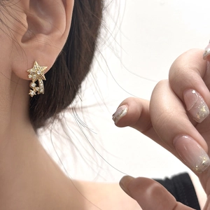 Elegant gold meteor stud earrings with micro-p鑲zirconia stars on a female model