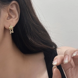 Close-up of elegant gold star-shaped earrings with sparkling crystals worn by a model
