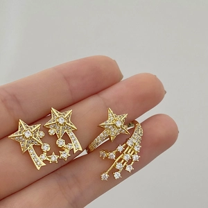 Detailed view of gold star-shaped earrings and ring set with sparkling zircons