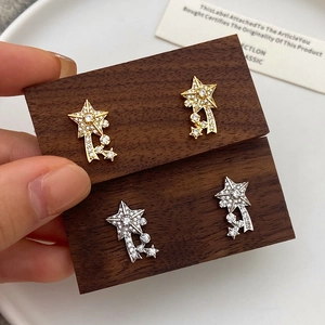 Detailed close-up of sparkling gold and silver star earrings with pavé crystal trails