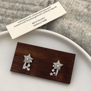 Detailed close-up of sparkling star-shaped stud earrings with zircon meteor trail on wood
