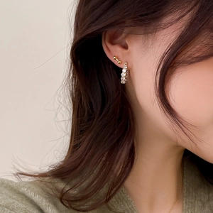 Gros plan de créoles et clous dorés avec diamants pavés sur l'oreille d'un modèle