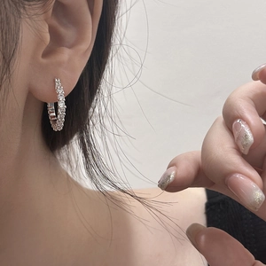 Détails de boucles d'oreilles créoles argentées pavées de cristaux sur le mannequin