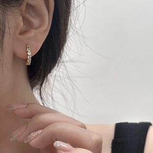 Détail de créoles dorées avec pavé de cristaux portées à l'oreille pour référence de taille