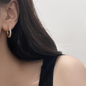 Gros plan de boucles d'oreilles créoles dorées serties de cristaux blancs étincelants
