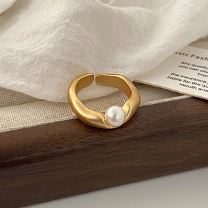 Vista macro dettagliata di un anello in oro opaco con un'elegante perla bianca