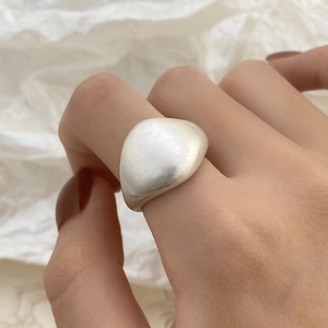 Detail of minimalist brushed metal irregular ring on a white textured background