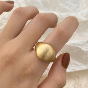 Minimalist brushed gold ring for women with unique irregular oval design on a white background