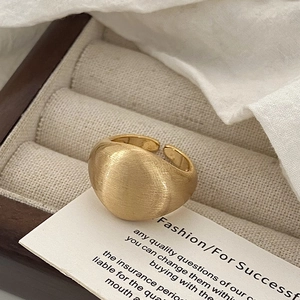 Macro detail of a wide brushed gold adjustable ring placed on a jewelry display card