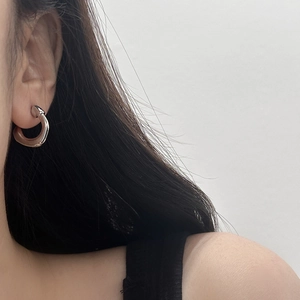 Créole argentée minimaliste en forme de C portée par un mannequin de style moderne