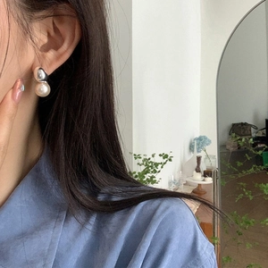 Close-up of pearl and silver bead earring worn by a model in a natural setting