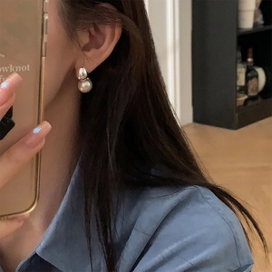 Close-up of minimalist pearl and silver bead earrings worn by model in a daily setting