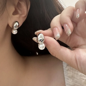 Close-up of minimalist silver metal bean earrings with elegant white pearl drops