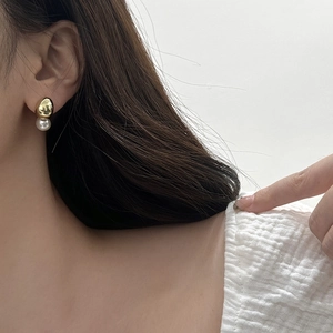 Close-up of gold water drop stud earrings with elegant white pearls on ear