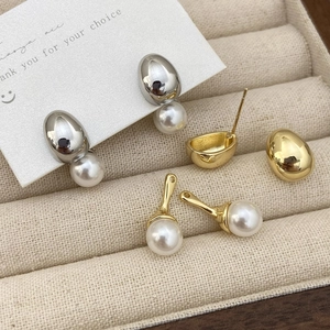 Detail view of gold and silver pearl earrings showing detachable components on a jewelry box
