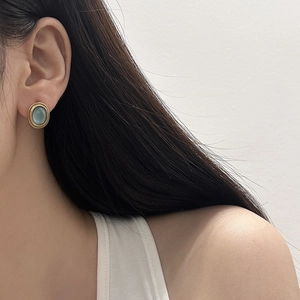 Elegant cat eye stone earrings in a round gold frame shown on a model for a vintage look