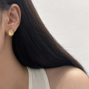 Detail of round cat eye stone earrings with gold metal bezel on a female model