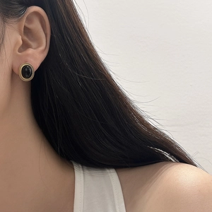 Close-up of elegant cat-eye geometric earrings with gold trim on a female model