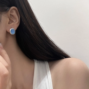 Detail view of silver cat-eye stone earrings worn by a model to show elegant style