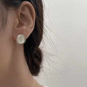 Detailed close-up of a silver cat's eye stone earring featuring a brushed metal texture