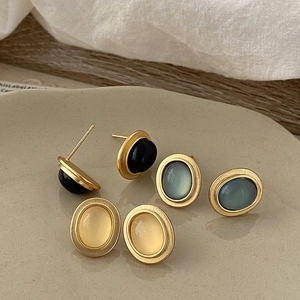 Detailed view of oval vintage cat eye stone earrings in matte gold set on a ceramic tray