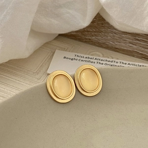 Detail of vintage oval cat eye stone earrings in matte gold set on a ceramic plate