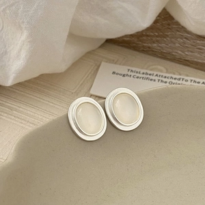Detail of silver oval vintage earrings with cat eye stones on a ceramic plate