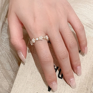 Detailopname van een bloemring met parels en zirkoon gedragen aan de vinger goud
