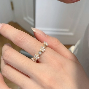 Detail van de gouden ring met kleine witte parels en fonkelende ronde zirkoniasteentjes