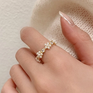 Close-up van een gouden parelbloemring met zirkoonaccenten gedragen door een model